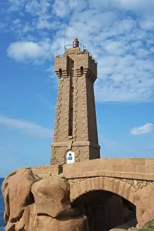 Coastal Area In Europe Drucke: Lighthouse above an arch of rocks in front of a blue sky with clouds