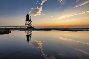 Lighthouse At Sunset Drucke: Lighthouse at sunset is reflected in water