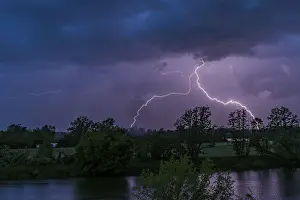 Dark Clouds Europe Drucke: Lightning during a night-time thunderstorm with dark clouds and dramatic atmosphere