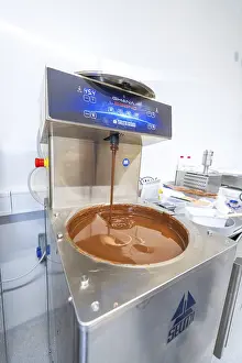 Christmas Sweets Drucke: Liquid chocolate flows out of a chocolate machine in a kitchen