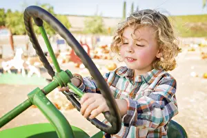 Rustic Ranch Setting Drucke: Little boy having fun in A tractor in a rustic ranch setting at the pumpkin patch
