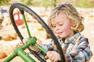 Rustic Ranch Setting Drucke: Little boy having fun in A tractor in a rustic ranch setting at the pumpkin patch