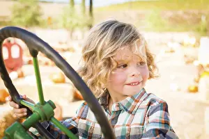 Rustic Ranch Setting Drucke: Little boy having fun in A tractor in a rustic ranch setting at the pumpkin patch