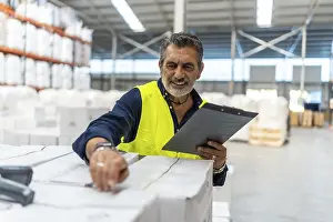 Commercial Logistics Services Drucke: Logistics manager smiling while using a barcode scanner