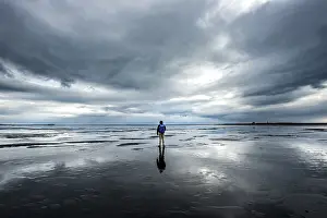 Icelandic Nature Tourism Drucke: Lonely hiker on the beach, dramatic clouds