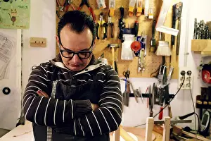 Traditional Craftsmanship Drucke: A luthier stands thoughtfully in his workshop