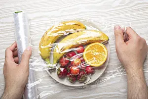 White Background Food Images Drucke: Male hands wrapping assorted different fruit