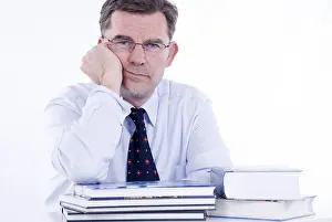 Office Worker Photo Drucke: Man, 50+, leaning on a stack of books