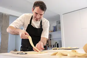 Breakfast Bread Nutrition Drucke: A man baking croissants picking up the triangular cuts from the puff pastry
