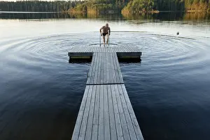 Serene Waterfront Scene Drucke: Man climbing onto dock
