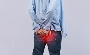 Digestive Problems Drucke: Man with digestive problem touching his buttock