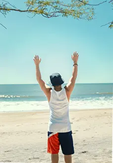 Young Man On Beach Drucke: Man with hat from behind on the beach