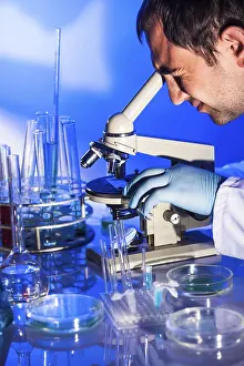 University Graduate Research Drucke: Man is looking into the ocular of microscope