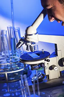 Laboratory Equipment Usage Drucke: Man is looking into the ocular of microscope