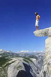 UNESCO World Heritage Site USA Drucke: A man makes a test of courage and stands on a ledge at the top of Half Dome