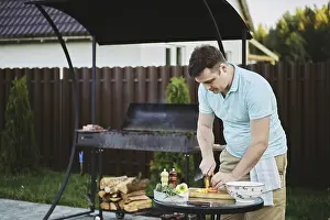 Healthy Meal Preparation Drucke: Man makes vegetable salad on backyard