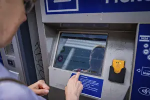 European Urban Environment Images Drucke: Man operates a ticket machine and is reflected in the display