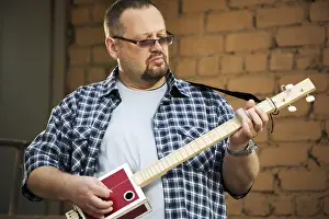 Musician Portrait Drucke: Man playing his three string cigar box guitar
