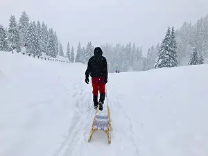 Snow Capped Mountain Landscape Drucke: Man pulling a sledge through the snow