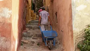 Byzantine Town Drucke: A man pulls a wheelbarrow up a narrow