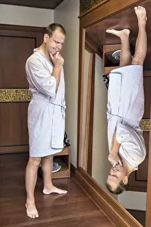 Rear View Of A Man Drucke: A man in a robe meditating when looking reverse reflection in the mirror
