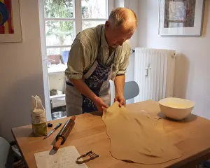 European Kitchen Utensil Drucke: Man rolling out strudel dough at a table