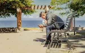 Young Man On Bench Drucke: Man sitting on a bench checking his phone