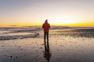 Evening Sky Reflections Drucke: A man stands on a beach at sunset