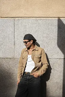 Urban Man Drucke: A man stands casually in front of a stone wall