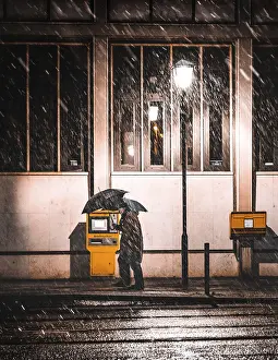 Central Europe Winter Scene Drucke: Man with umbrella in snow in front of mailboxes