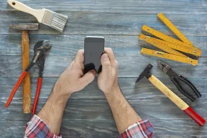 Carpenter At Work Drucke: Man working on a DIY project with his phone