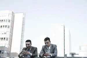 Young Business Professionals Drucke: Two managers checking their smartphones during a break
