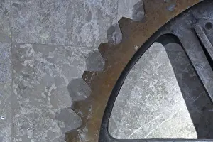 Industrial Equipment Drucke: Part of a massive rusty gear on a stone wall background