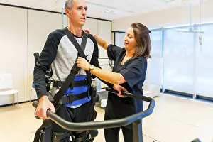 Physical Disability Support Drucke: Mechanical exoskeleton. Female physiotherapy medical assistant with disabled person lifted with robotic skeleton