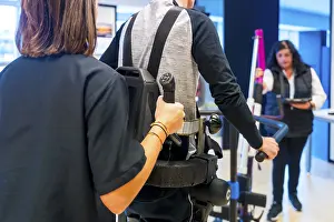 Mechanical Exoskeleton Drucke: Mechanical exoskeleton. Female physiotherapy medical assistant helping disabled person with robotic skeleton to walk