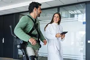 Mechanical Exoskeleton Drucke: Mechanical exoskeleton, female doctor physiotherapist with disabled person with robotic skeleton in rehabilitation