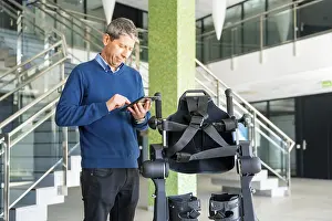 Mechanical Exoskeleton Drucke: Mechanical exoskeleton computer engineer looking at the robot with a tablet
