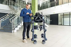 Physiotherapy Robot Drucke: Mechanical exoskeleton computer engineer looking at the robot with a tablet