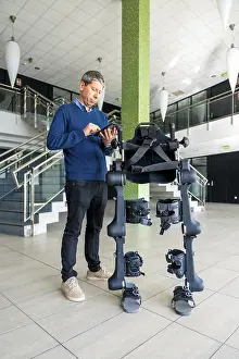 Mechanical Exoskeleton Drucke: Mechanical exoskeleton computer engineer looking at the robot with a tablet