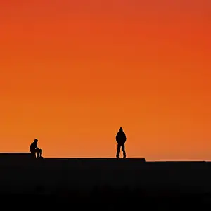 North African Evening Light Drucke: Two men, silhouettes on a wall at sunset