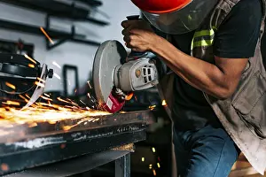 Industrial Technology Drucke: Metalworking professional using an angle grinder in the workshop