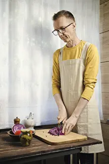 Cabbage Vegetable Health Benefits Drucke: Middle-aged man chopping red cabbage in the kitchen
