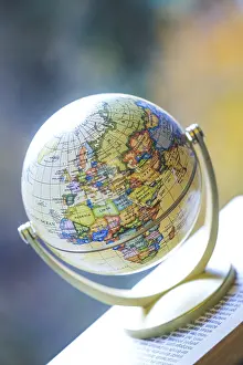 Travel Photography Drucke: Miniature globe model standing on a stack of books