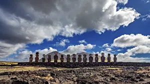 Easter Island Drucke: Moai statues stand under a sky with dramatic clouds on a rocky surface