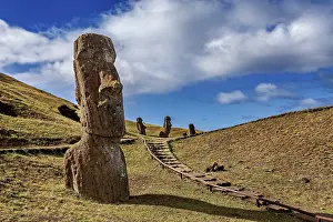 Easter Island Moai Drucke: Several moais on a hill with a path surrounded by blue sky and clouds