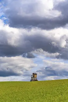 Cloudy Landscape Drucke: Mobile raised hide in an empty field under dramatic clouds