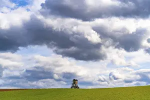 Deserted Farmland Germany Drucke: Mobile raised hide in an empty field under dramatic clouds