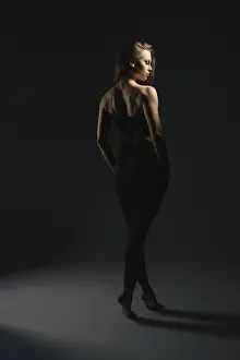 Elegant Woman Portrait Drucke: A model stands elegantly under soft lighting in a dark studio