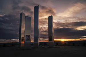 Deserted Evening Sun Germany Drucke: Modern sculptures in front of a dramatic sunset sky with reflections