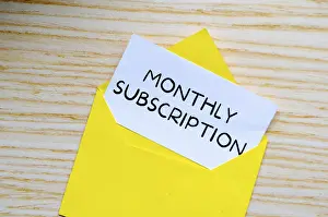 Bright Background Copy Space Drucke: Monthly Subscription text on white notepad inside a yellow envelope